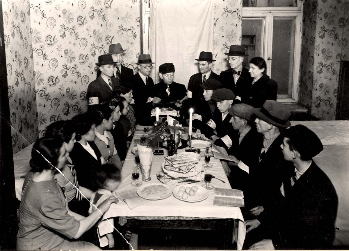Warsaw, Poland, Jews around a seder table in a shelter on 6 Leszno St. in the ghetto, reading from the Passover Haggada